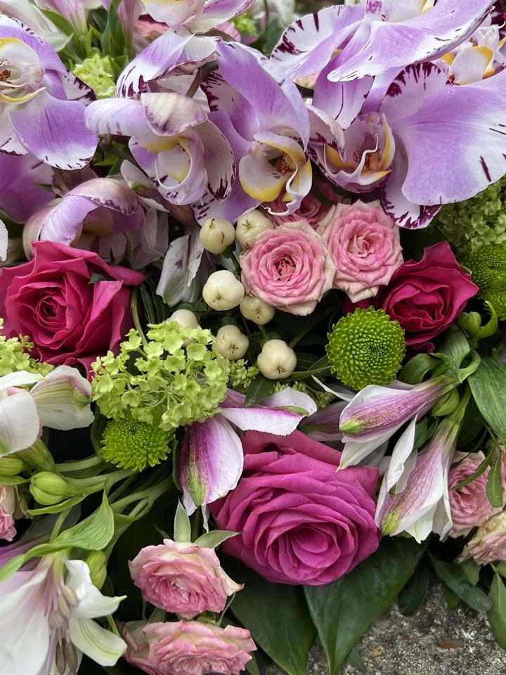 Détail d'un bouquet d'orchidées, de roses roses et de feuillages réalisé en formation